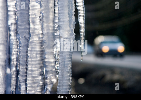 Icicles at roadside with car in backgound Stock Photo