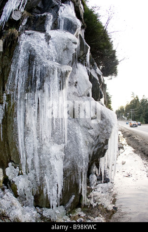 Icicles at roadside with car in backgound Stock Photo