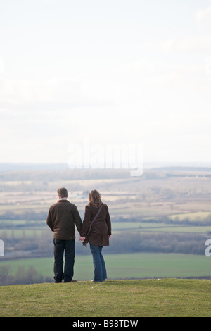 Middle aged couple holding hands on a hillside looking at the view Stock Photo