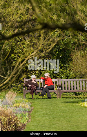 Two mature women chatting on park bench, UK Stock Photo