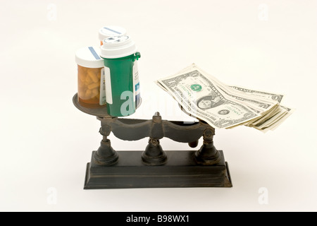 Balance scale with money on one side and prescription containers on the other Stock Photo