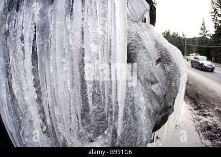 Icicles at roadside with car in backgound Stock Photo