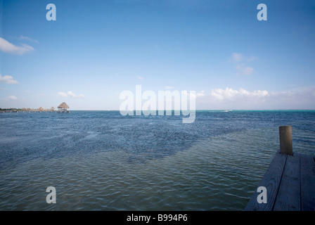Approaching sunset in the late afternoon while sitting on a dock over calm water on Ambergris Caye in Belize. Stock Photo