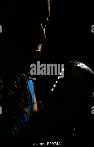Young woman singing into a retro microphone Stock Photo