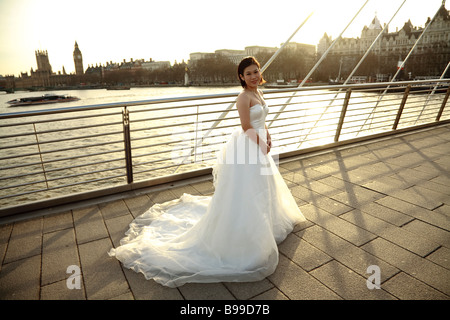 an asian bride in wedding dress in front of cityscape of london, River Thames and Westminster with Big Ben Stock Photo
