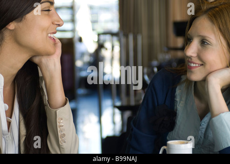Two female friends having coffee and chatting in cafe Stock Photo