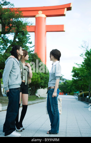 Group of friends chatting, traditional Japanese Torii gate in background Stock Photo