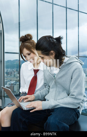 Young couple sitting on windowsill, using laptop computer Stock Photo