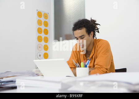 Man working at desk, arms folded Stock Photo
