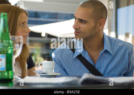 Man and woman sitting in outdoor cafe, having serious conversation Stock Photo
