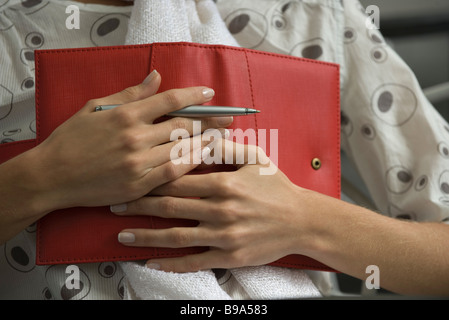 Woman holding diary on chest, cropped view Stock Photo