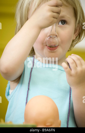 Toddler girl eating with plastic spoon, close-up Stock Photo