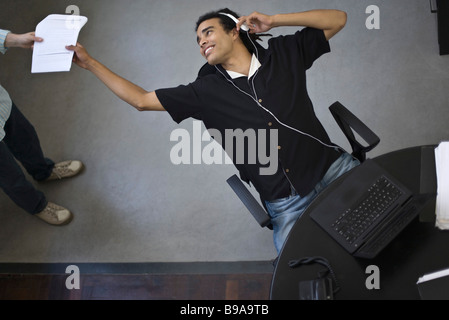 Young office worker leaning back in chair to receive document from colleague, high angle view Stock Photo