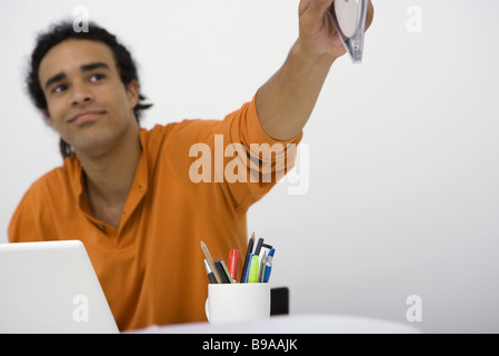 Man sitting at desk, holding out CD Stock Photo