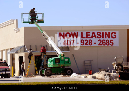 cherry picker boom lift at building construction site with now leasing sign Stock Photo