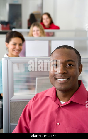 Businessman and co workers sitting in cubicles Stock Photo
