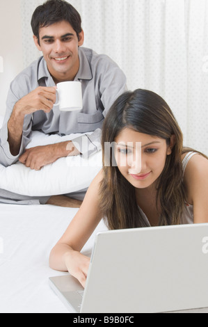 Woman working on a laptop while her husband drinking tea Stock Photo