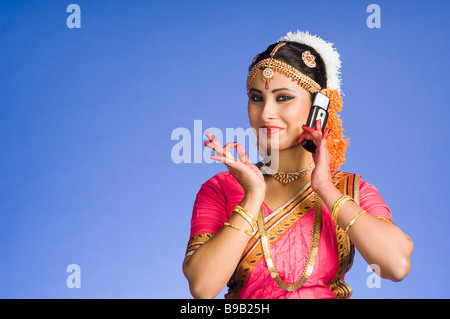 Female Dancer talking on a mobile phone in and performing Bharatnatyam Stock Photo