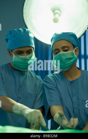 Two female surgeons performing a surgery in an operating room Stock Photo