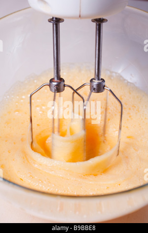 Whisking eggs with cake ingredients with electric mixer Stock Photo