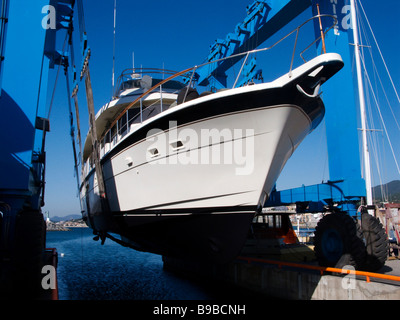 Semi displacement motor yacht on travel lift being put back into the water Stock Photo