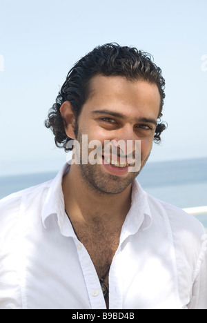 Young ethnic man by the sea smiling Stock Photo
