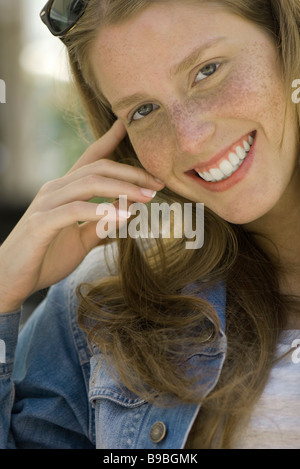 Young woman with freckles smiling at camera, portrait Stock Photo