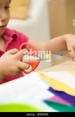 Little girl using scissors to cut paper, cropped view Stock Photo