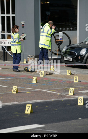 Forensic police take evidence after a road traffic accident leaves a car on the pavement, on Clapham High Street, south London. Stock Photo