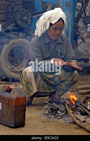 Burmese day labourer sitting on small fire at the ferry station of Mandalay Myanmar Stock Photo