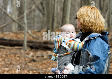 Baby being carried by mother in woods Stock Photo