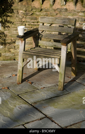 Wooden garden seat on patio slabs with mug Stock Photo