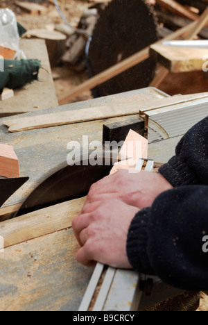 Man operating circular saw crosscutting angled timber components Stock Photo