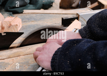 Man operating circular saw crosscutting angled timber components Stock Photo