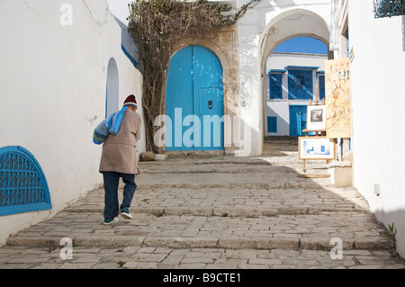 Man walking up steps along cobbled street in Sidi Bou Said, Tunisia, North Africa Stock Photo