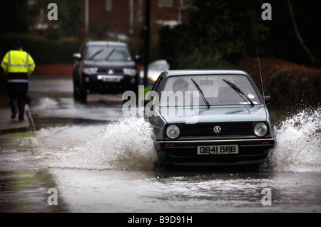 A SMALL CAR NEGOTIATES FLOODWATER FOLLOWED BY A FOUR WHEEL DRIVE VEHICLE IN THE VILLAGE OF STONEHOUSE NEAR STROUD GLOUCESTERSHIR Stock Photo