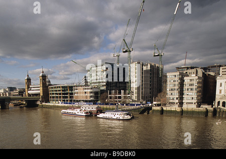 View of City of London Thames frontage between Cannon Street Station and London Bridge, under stormy sky. Stock Photo