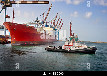 tugboat pulling a cargo ship away from the dock Stock Photo