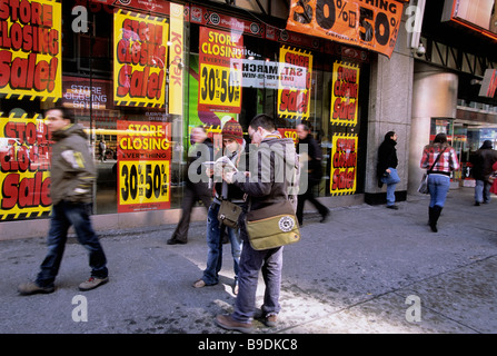 New York going out of business liquidation sale.Tourists looking at a map on the street in front of closing store on Broadway in Midtown Manhattan USA Stock Photo