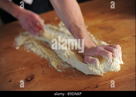 hands kneading bread on a kitchen table Stock Photo
