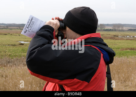 A birdwatcher looks through his binoculars on the coastal route from Burnham Deepdale to Burnham Overy Norfolk England Stock Photo