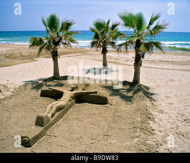 Crucifix, sand art on Calp Beach, Calpe, palm trees, Costa Blanca, Alicante Province, Spain Stock Photo