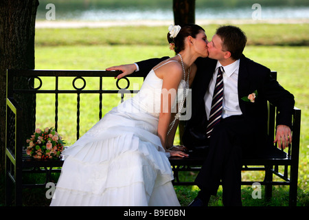 Newlywed young couple kissing on park bench Stock Photo