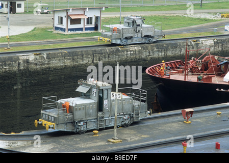 Trains or 'mules' guiding container ship in Gatun locks, Panama Canal Stock Photo