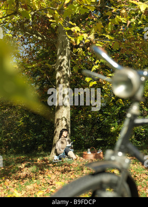 Mature woman leaning against tree in park Stock Photo
