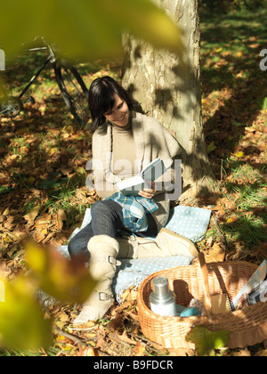 High angle view of mature woman reading book under shadow of tree Stock Photo