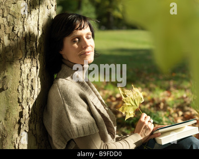 Close-up of mature woman resting against tree Stock Photo