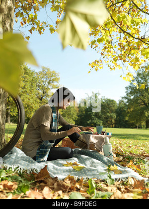 Side profile of mature woman applying cheese on slice in park Stock Photo