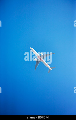 Emirates Airlines Boeing 777-300ER in flight against a clear deep blue sky Stock Photo