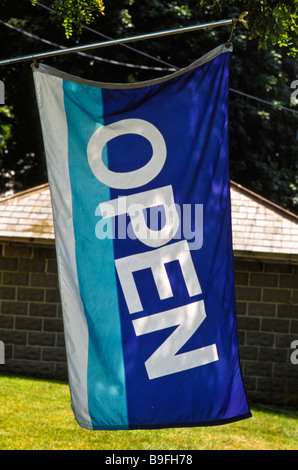 blue white open sign flag on tree of antique crafts souvenier store Lancaster PA Stock Photo